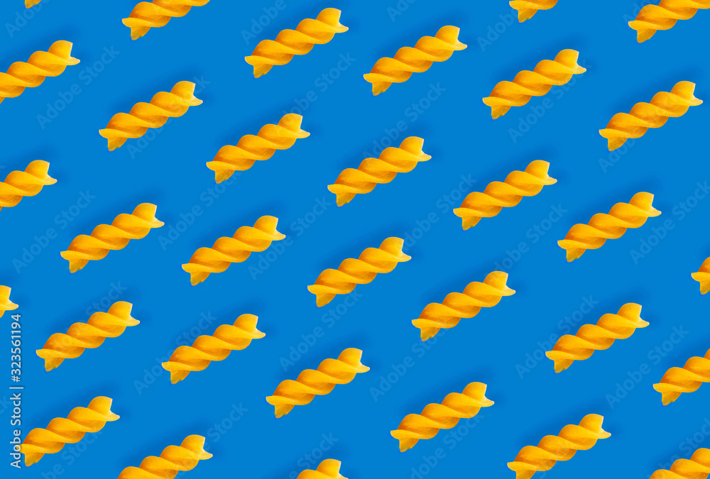 Diagonal spiral paste on a blue background, top view, Italian dish, symmetrical layout, gluten-free product, spiral paste background, yellow on blue, everyday dish Diagonal spiral paste on a blue background, top view, Italian dish, symmetrical layout, gluten-free product, spiral paste background, yellow on blue, everyday dish