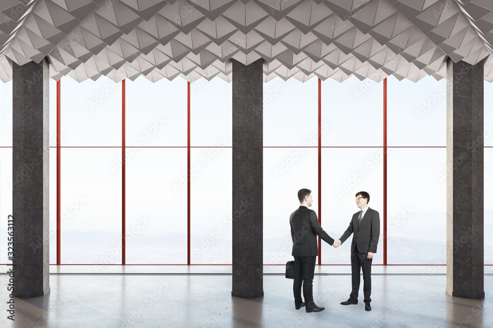 Fototapeta premium Business people shake hands in modern concrete interio