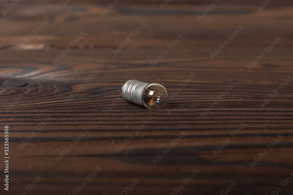 Control lamp - a small lamp at 6.3 W, used in control, measuring, calculating devices. lies on a wooden surface Control lamp - a small lamp at 6.3 W, used in control, measuring, calculating devices. lies on a wooden surface