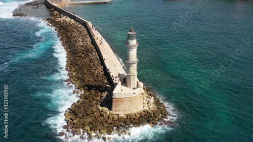Aerial drone video of iconic Venetian lighthouse in the entrance of picturesque old port of Chania with beautiful colours, Crete island, Greece. Lighthouse in Chania. Lighthouse of the city of Chania.