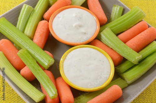 Raw carrots and celery vegetable snack plate for two with small bowls of ranch dressing