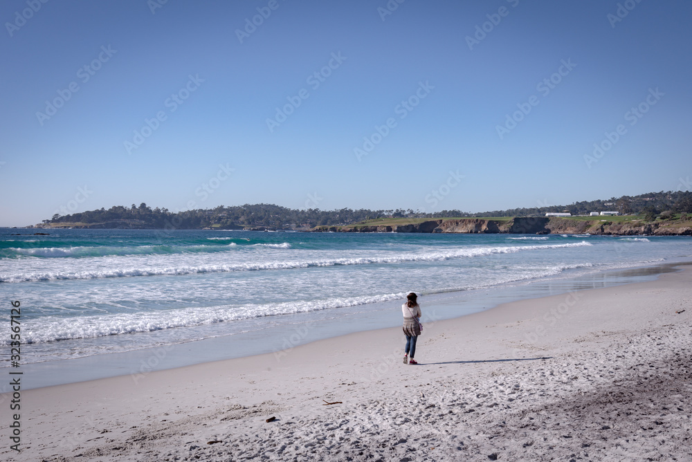 A woman walks alone on the seashore