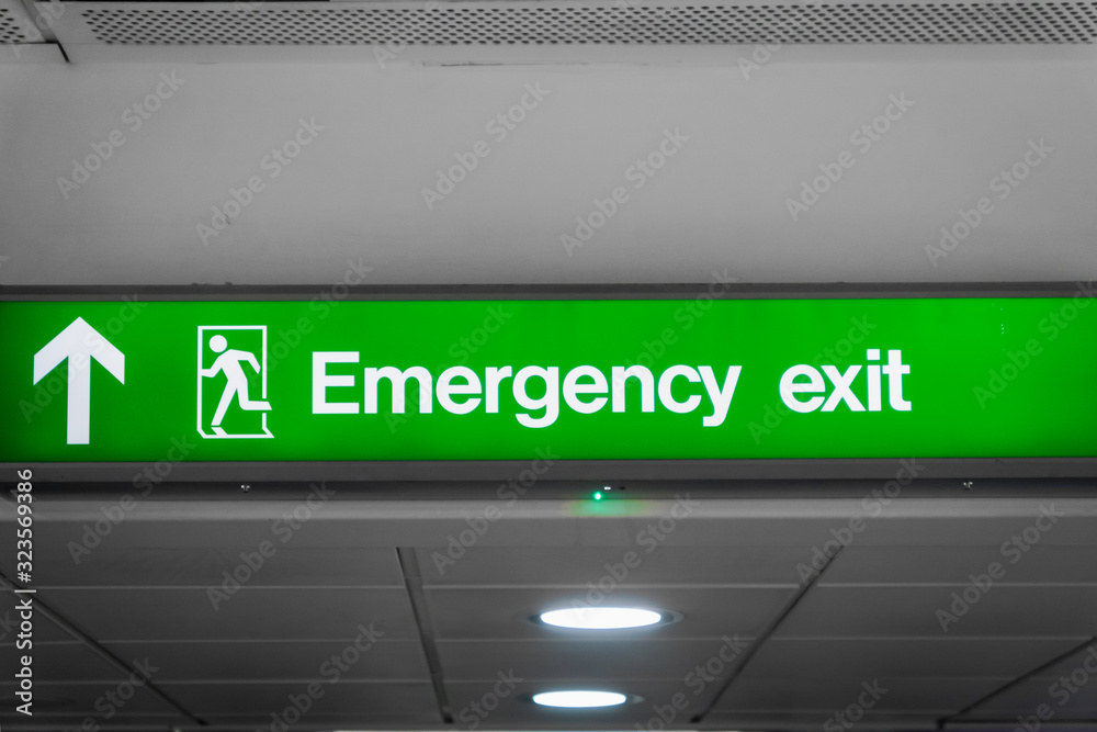 Emergency exit sign glowing green in airport- for safety, fire drill ...