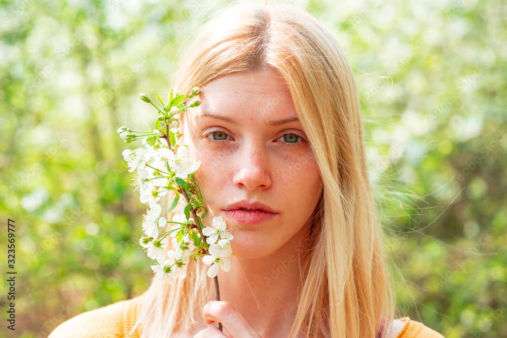 Beautiful woman portrait close up. Woman on background with flowers on a spring day.