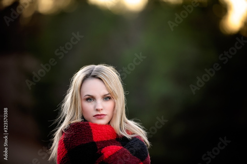 blonde headed girl looking at camera wrapped in a red and black blanket