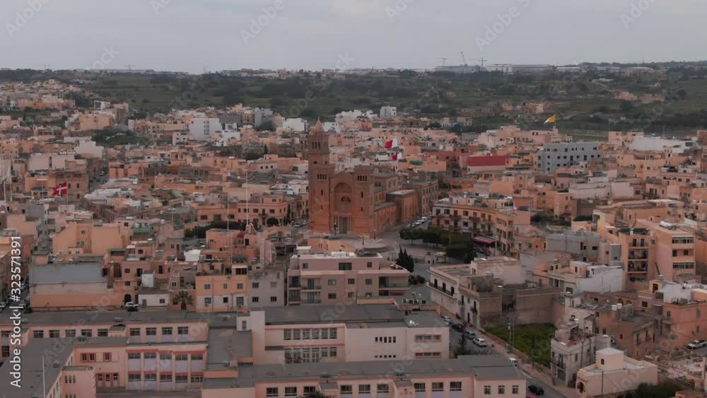 Flies back from a church in the center of the old city on the island of Malta in Europe. Roofs of houses in the frame, nature on the background. Aerial video Flies back from a church in the center of the old city on the island of Malta in Europe. Roofs of houses in the frame, nature on the background. Aerial video