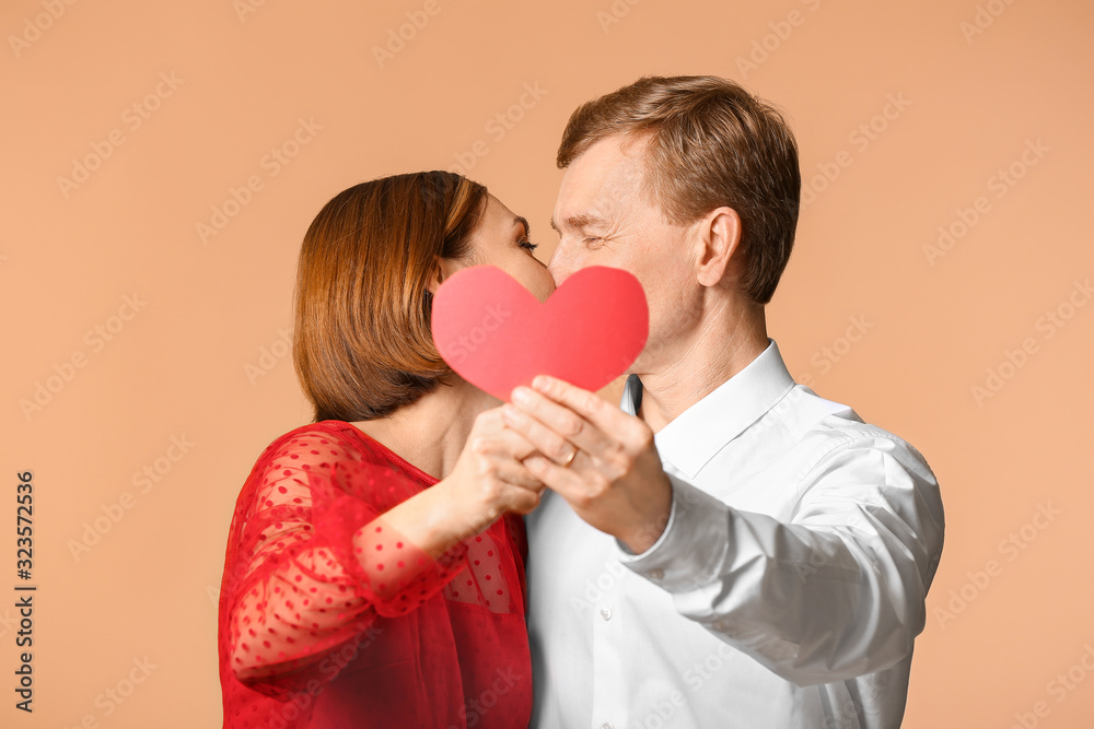 Portrait of beautiful couple with red heart on color background Portrait of beautiful couple with red heart on color background