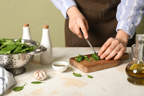 Woman cutting fresh spinach at table