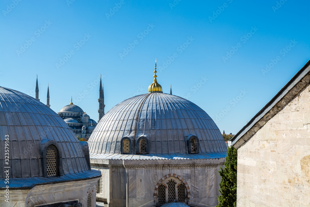 Domes of complex of Hagia Sophia, the former Greek Orthodox Christian patriarchal cathedral, later an Ottoman imperial mosque and now a museum in Istanbul, Turkey and background of Sultan Ahmed Mosque