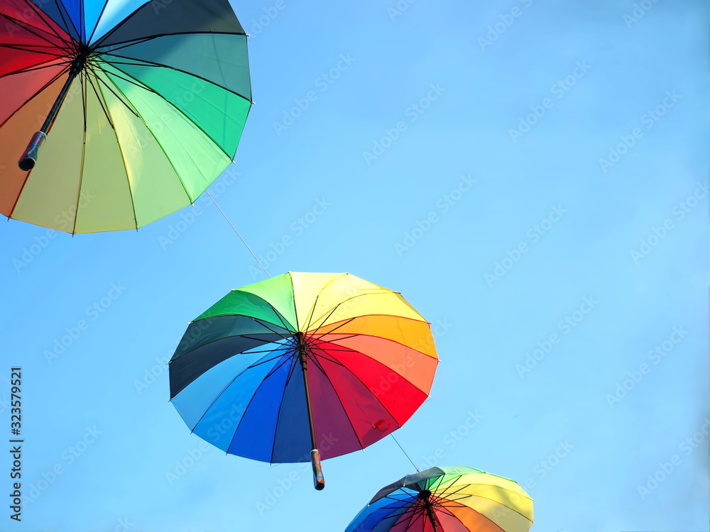 Multicolored umbrellas hung on a bright blue sky with copy space. Selective focus