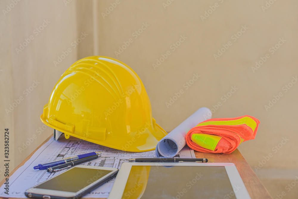 Yellow hard hat for Engineer Foreman Supervisor at construction site is on office desk Yellow hard hat for Engineer Foreman Supervisor at construction site is on office desk