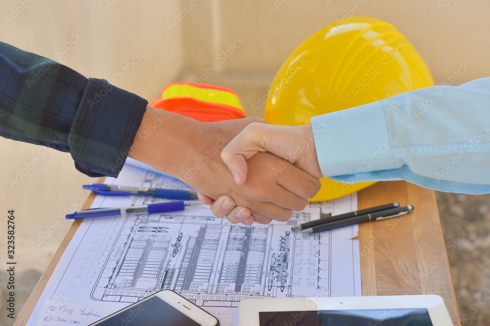 Close up People Shake hand at blueprint construction site background concept,Engineer hand shake success building project Close up People Shake hand at blueprint construction site background concept,Engineer hand shake success building project