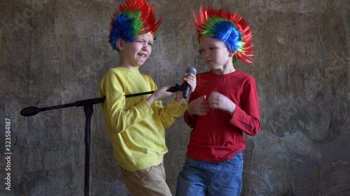 Two crying boys received latest smartphone models as gift from their parents. children turned on music, dressed in punk Iroquois carnival wigs and sang karaoke in front of microphone on stand