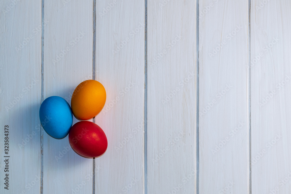 colored Easter eggs on white wooden boards top view. red, blue, orange, holiday background. colored Easter eggs on white wooden boards top view. red, blue, orange, holiday background.