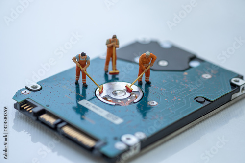 Miniature People: Worker cleaning professional repairman holding a cleaning brush inside old personal computer. Harddisk cleaning and maintenance concept, close up view.