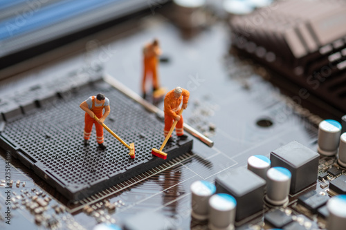 Miniature People: Worker cleaning professional repairman holding a cleaning brush inside old personal computer. CPU cleaning and maintenance concept, close up view.