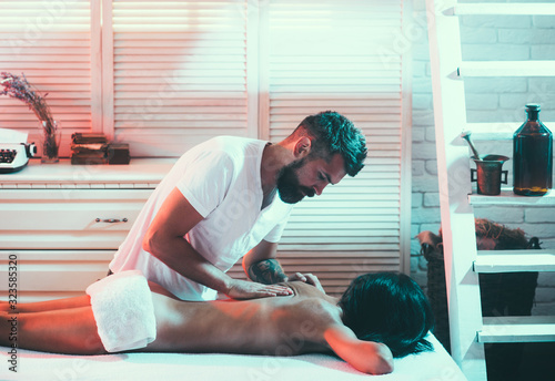 Taking care about lover concept. Relaxation and foreplay of couple in love. Handsome loving husband doing massage spa procedure carefully and tenderly for his beautiful wife.