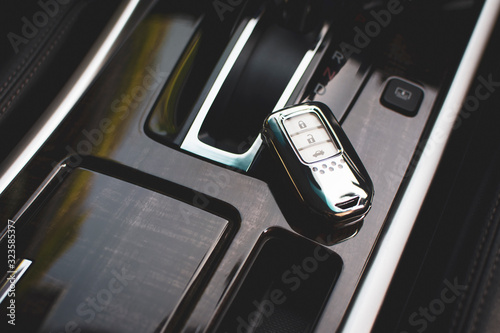 The car keyless remote is chrome color placed at the luxury car console. photo