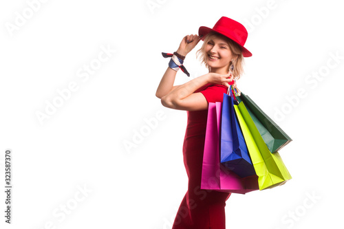 blonde girl with short hair on isolat in a red dress and a red hat, with colored paper shopping bags. The concept of shopping or sales,