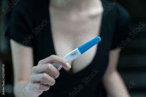 Female hand holding negative pregnancy test, with not pregnant results.