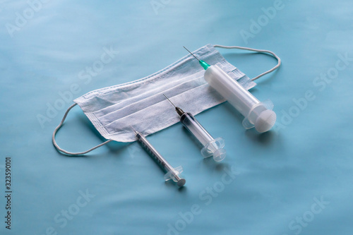 medical mask for protection against bacteria on a blue background. Near syringes for injection. Close-up