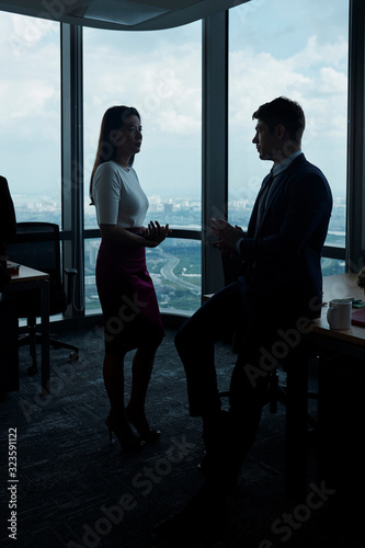 Business people having serious conversation in dark office with big panoramic windows © DragonImages