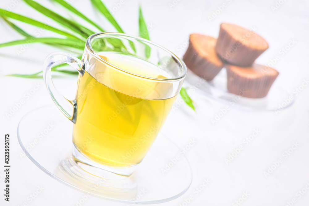 Herbal ginger tea in clear glass On a white background with a cake backdrop Tables for drinks, healthy ideas.soft focus.