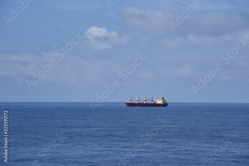 Landscape of the calm ocean with sailing cargo ship. 