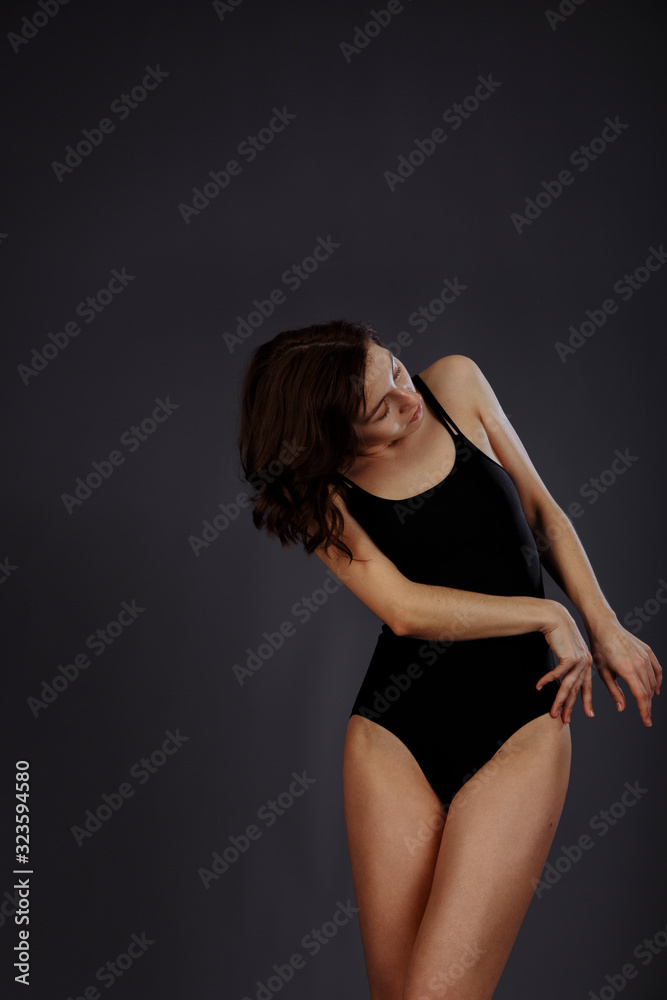 A brunette in a black swimsuit strokes her thigh. A brunette in a black swimsuit strokes her thigh.