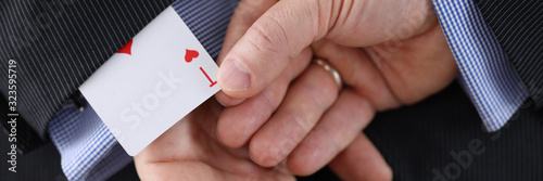 Close-up of cheater hands pulling ace card out of sleeve with crossed arms behind. Gamer with strong addiction to games. Bribe casino and dishonesty concept photo