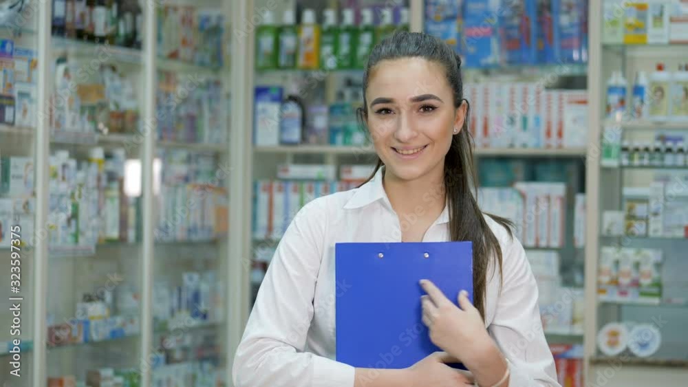 Smiling young pharmacist posing with a planchette in hands in the pharmacy Smiling young pharmacist posing with a planchette in hands in the pharmacy