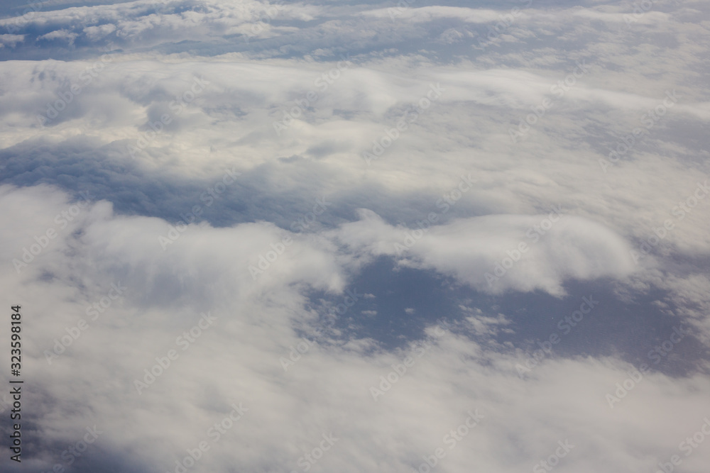 Aerial sky and fluffy clouds background. View from airplane porthole