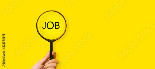 job search concept, inscription and magnifier in hand on a yellow background photo