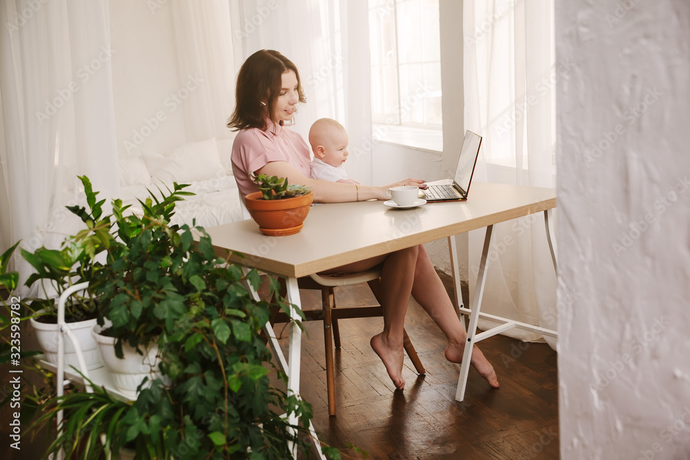 mom and baby. a young mother working with laptop at home.