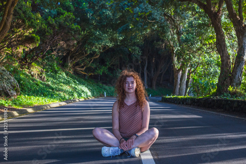 Woman sitting with crossed legs at the road in the forest. Terceira, Azores. Portugal photo