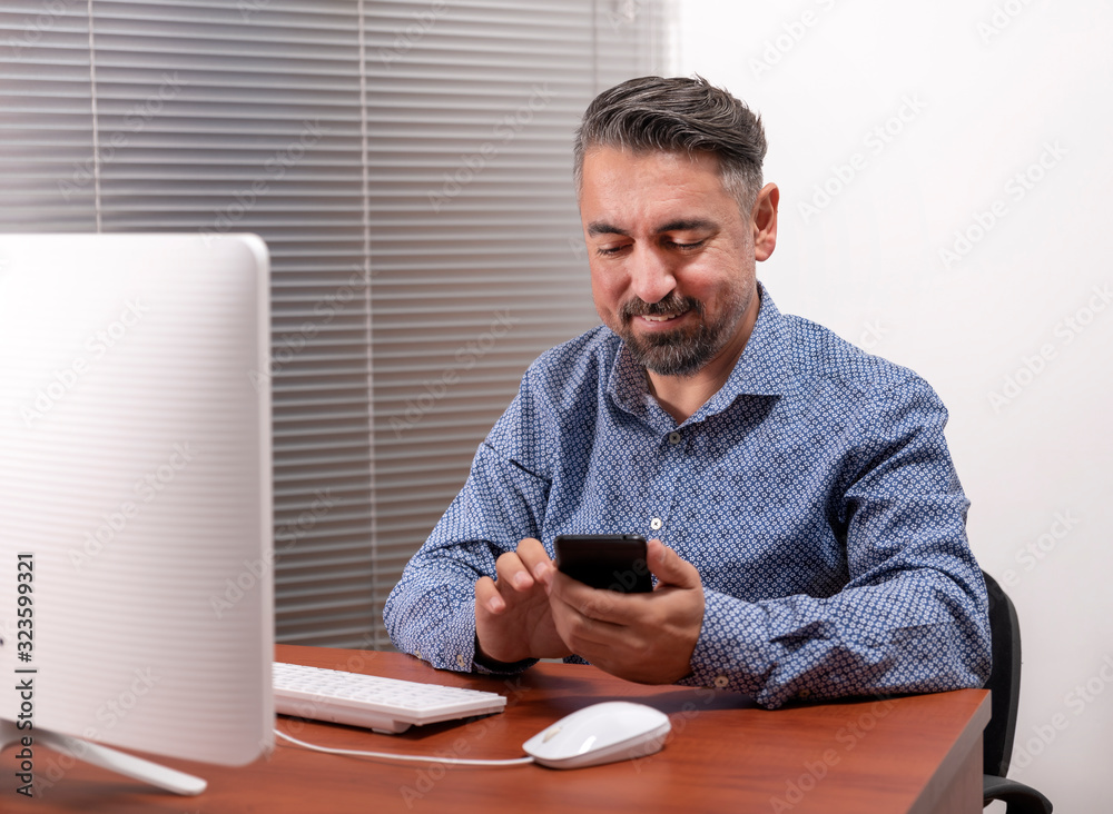 Portrait Of A Happy Mature Man Using Desktop Computer And Smart Phone