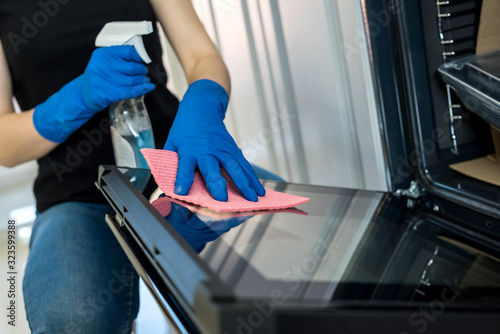 young woman cleaning the oven with rubber gloves and rag. cleaning concept.