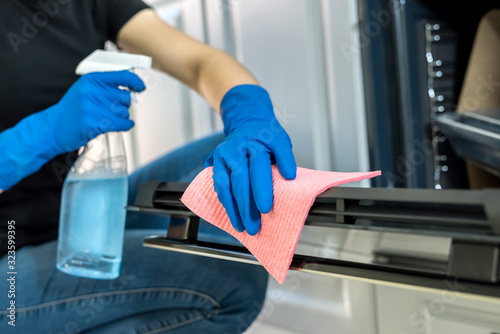 young woman cleaning the oven with rubber gloves and rag. cleaning concept.