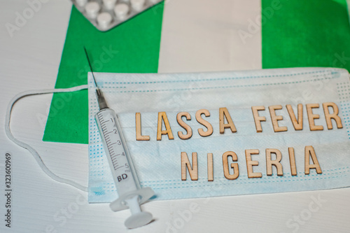 Nigerian flag under words Lassa fever outbreak concept. protective breathing mask and syringe. Lassa hemorrhagic fever LHF endemic in West Africa including Sierra Leone, Liberia, Guinea and Nigeria photo