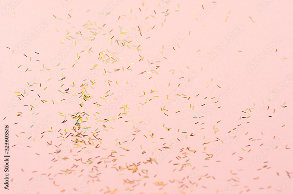 Gold holographic glitter on pink background, abstract texture.