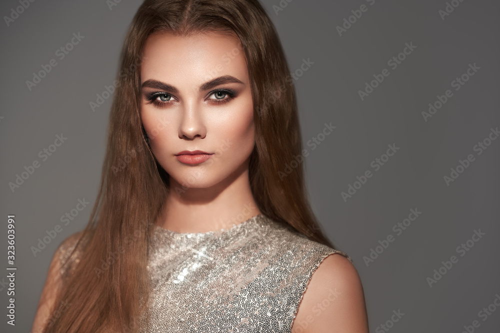 Portrait beautiful woman with jewelry. Brunette girl with long smooth hair. Beauty fashion. Eyelashes. Cosmetic eyeshadow. Care and beauty hair products. Model in a silver dress Portrait beautiful woman with jewelry. Brunette girl with long smooth hair. Beauty fashion. Eyelashes. Cosmetic eyeshadow. Care and beauty hair products. Model in a silver dress