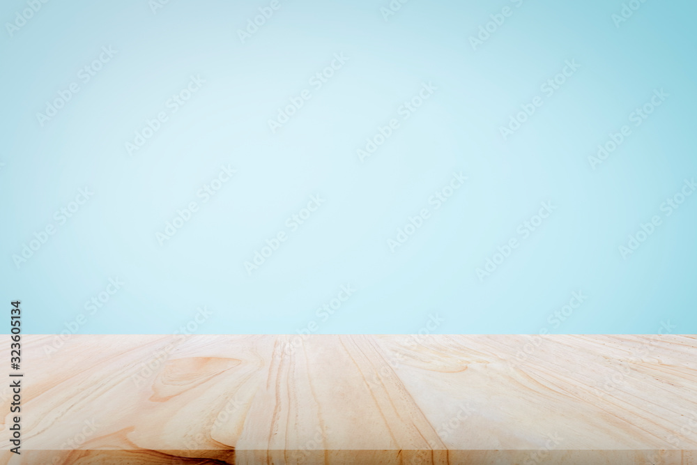 Empty wooden deck table over light blue wallpaper background for present product. - obrazy, fototapety, plakaty 