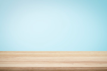 Empty wooden deck table over light blue wallpaper background for present product.