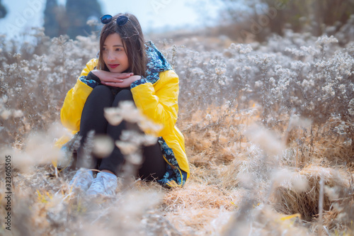 Fototapeta Naklejka Na Ścianę i Meble -  Beautiful girl in a yellow jacket with a dry flower field