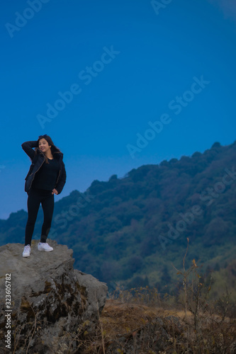 A young woman standing on a rock on a cliff