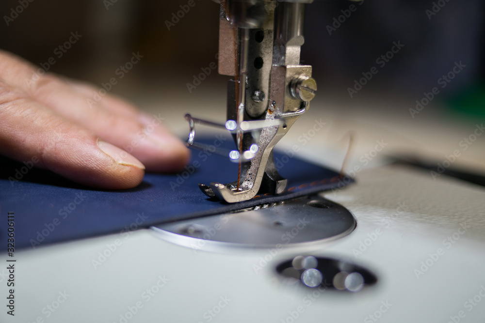 A man sews from leather on a sewing machine. Hands and sewing. Production of leather goods using a sewing machine