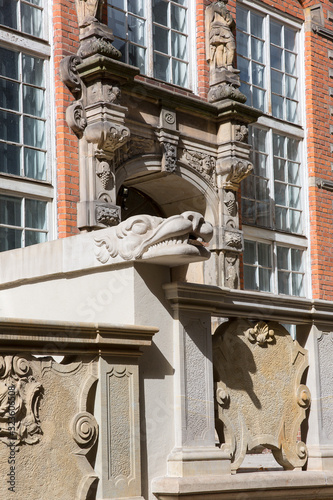 Grotesque gargoyle on front of colorful tenement house, Gdansk, Poland