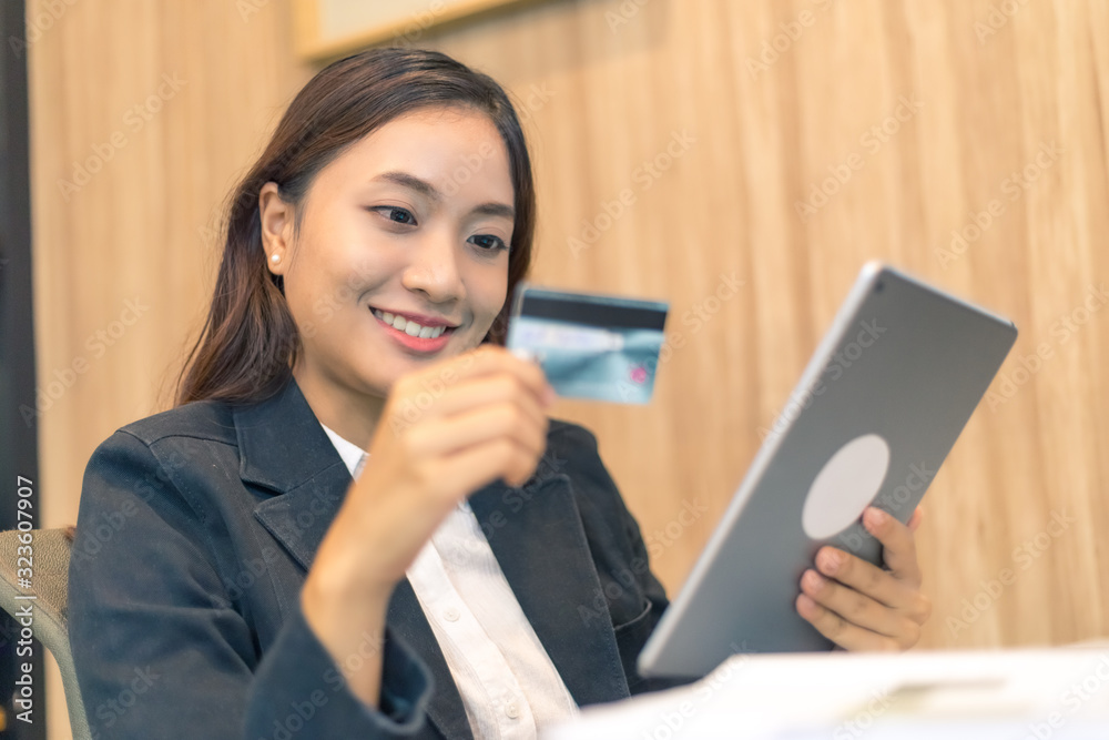 Business asian woman using credit card and tablet for online shopping in the office, fresh and happy feeling Business asian woman using credit card and tablet for online shopping in the office, fresh and happy feeling