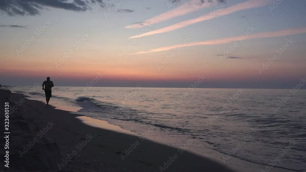 silhouette a man walking peacefully along a deserted beach at sunrise. seascape silhouette a man walking peacefully along a deserted beach at sunrise. seascape