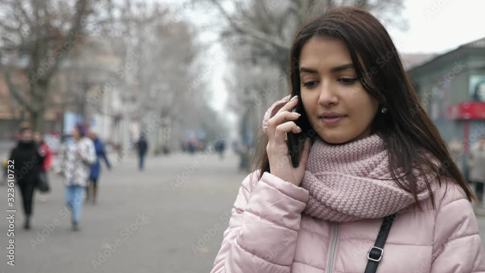 Stylish and nice girl smiling and talking by phone in an airy street in autumn Stylish and nice girl smiling and talking by phone in an airy street in autumn